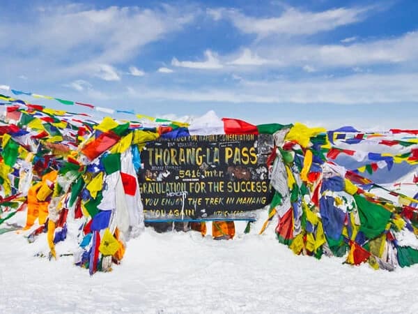 Along the Annapurna Circuit walk, vibrant prayer flags flutter in the wind